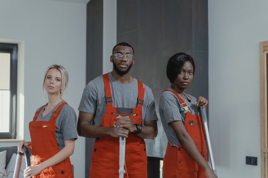 A diverse team of cleaning professionals in uniform posing in an indoor setting.